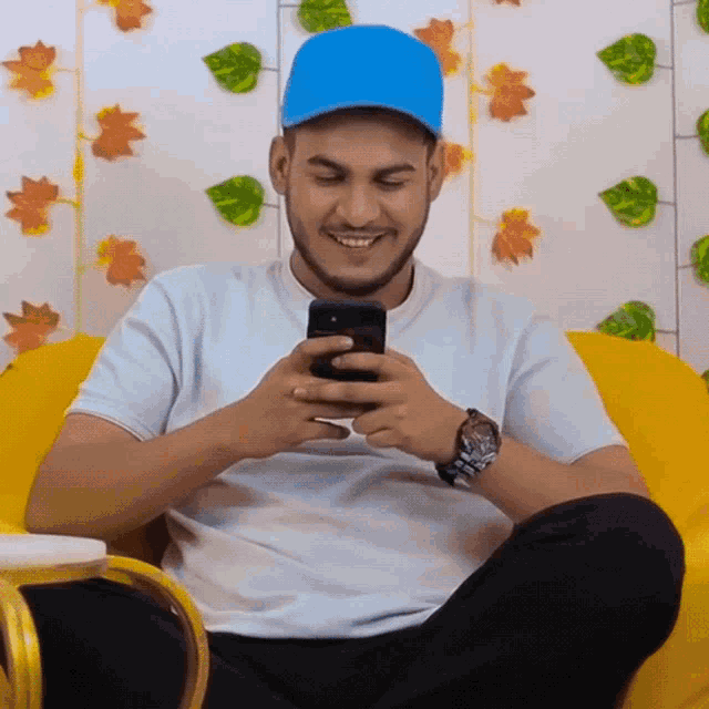 a man wearing a blue hat is smiling while looking at his cellphone
