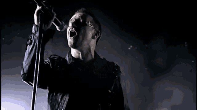 a man is singing into a microphone on a stage .