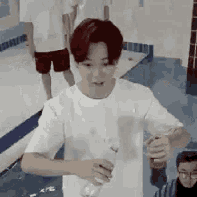 a man in a white shirt is holding a bottle of water .