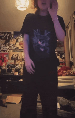 a person standing in a room with posters on the wall including one that says ' hellfire '