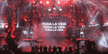 a group of people are standing in front of a stage that says toda la vida