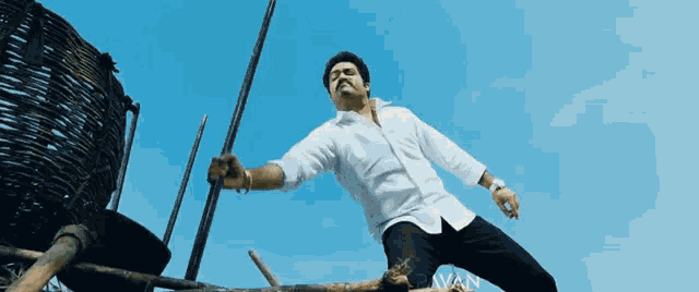 a man in a white shirt and black pants is holding a pole in his hand