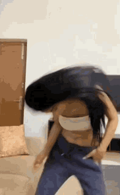 a woman is dancing on a couch with her hair in the air .
