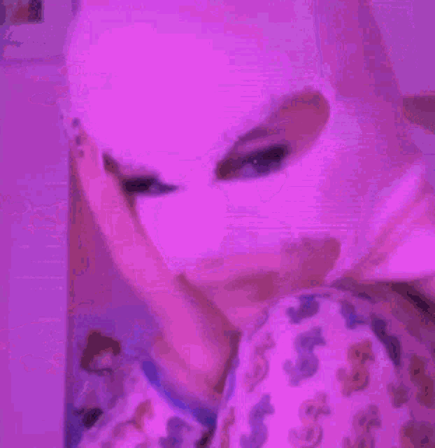 a person wearing a ski mask is laying on a bed in a pink room .