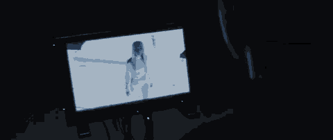 a person is looking at a screen with a picture of a woman on it in a dark room .