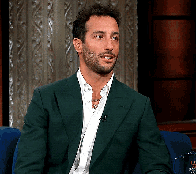 a man with a beard wearing a green jacket and white shirt