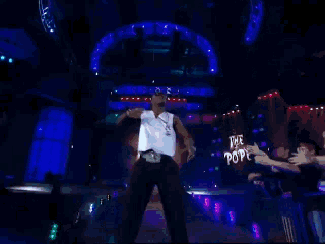 a man stands on a stage with a sign that says dinero in the background