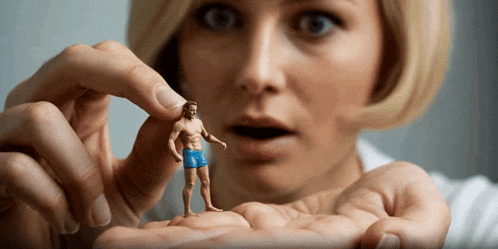 a woman is holding a small figurine of a man