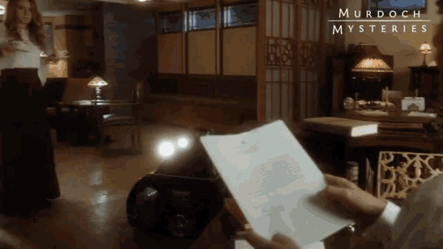 a poster for murdoch mysteries shows a woman and a man in a living room