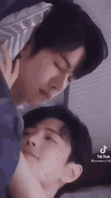 a couple of men laying next to each other in bed .