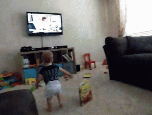 a baby in a diaper is running in front of a television