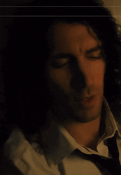 a man with curly hair is wearing a white shirt and a black tie