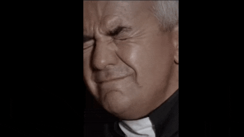 a close up of a priest making a funny face with his eyes closed .