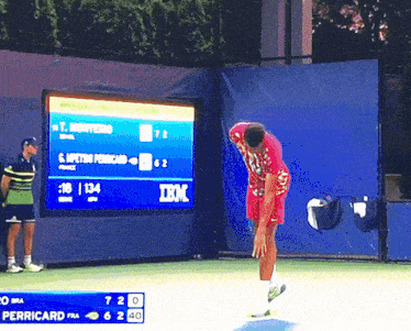 a man stands on a tennis court in front of a scoreboard with ibm written on it