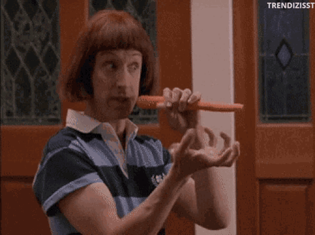 a man with a wig is holding a carrot in his mouth .