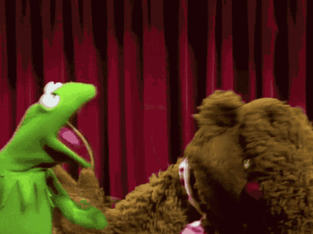 kermit the frog and mrs. piggle bear are standing next to each other on a stage in front of a red curtain