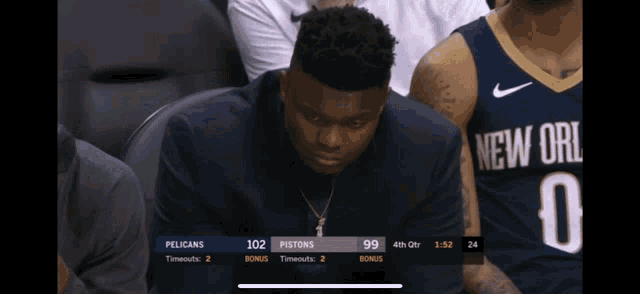 a man in a new orleans jersey sits in the stands watching a game