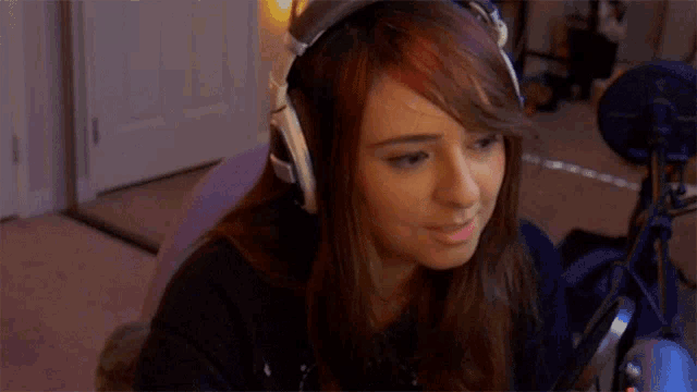 a woman wearing headphones is sitting in front of a microphone in a room