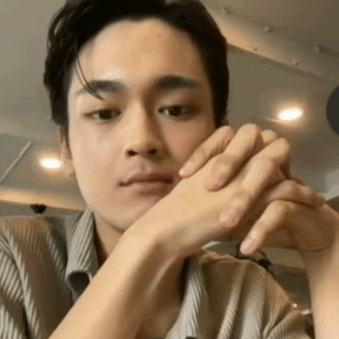 a close up of a man 's face with his hands folded .