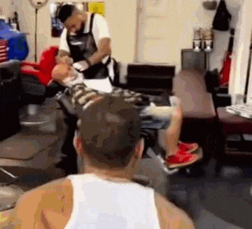 a man is getting a haircut at a barber shop .