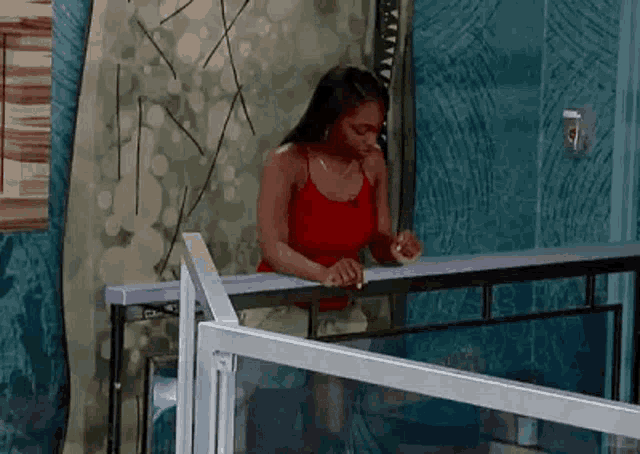 a woman in a red tank top is sitting on a balcony .