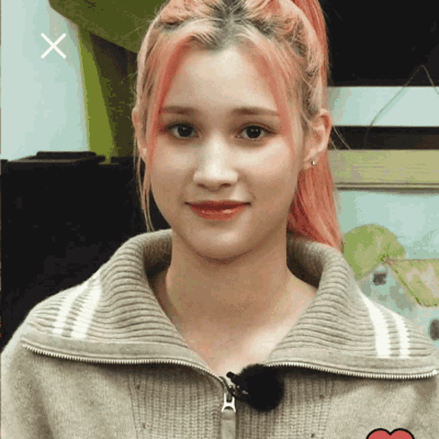 a woman with pink hair is wearing a sweater with a zipper