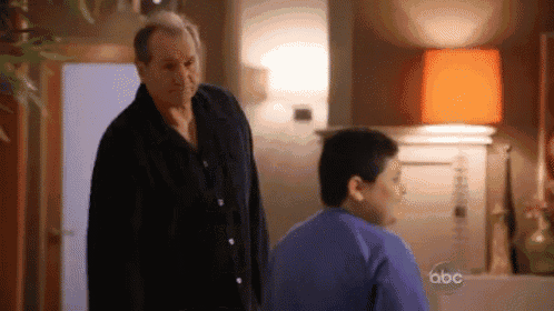 a man is standing next to a boy in a living room .