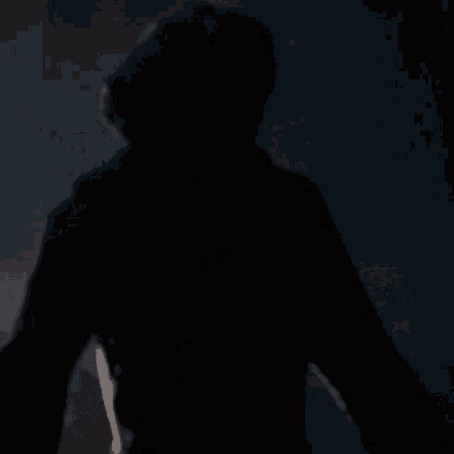 a man is standing in the dark in a dark room with a mask on his face .
