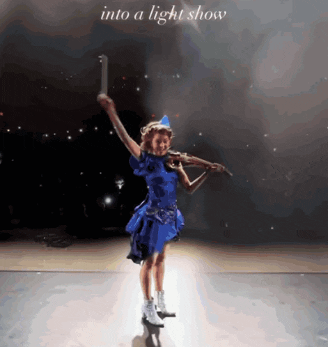 a little girl in a blue dress is playing a violin on a stage with the words into a light show behind her