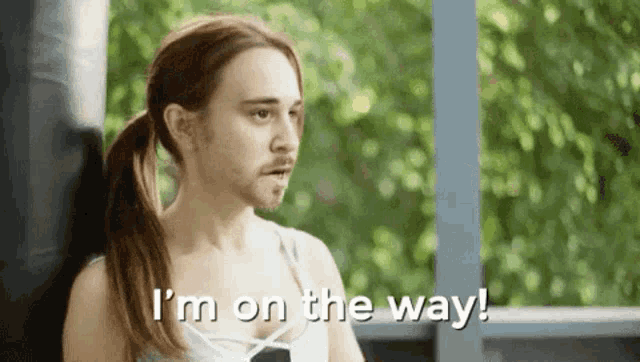 a man with a ponytail and a beard is saying i 'm on the way .