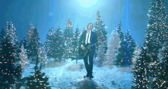 a man is playing a guitar in a snowy forest