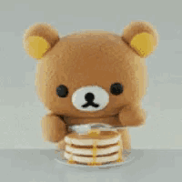 a teddy bear is eating a stack of pancakes