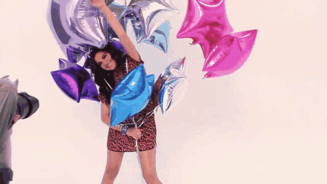 a woman is holding a bunch of balloons in her hand