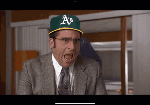 a man in a suit and tie is wearing a a 's baseball cap