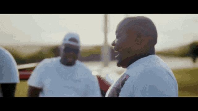 a group of men in white shirts are standing in a field and laughing .