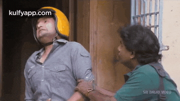 a man wearing a helmet is talking to another man while another man holds his arm .