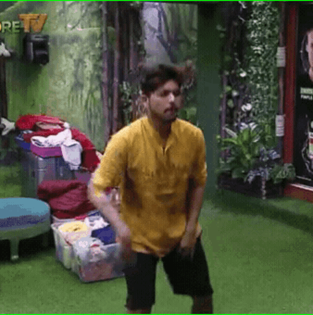a man in a yellow shirt is dancing in a room with a sign that says ' re tv ' on it