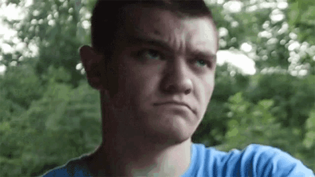 a young man in a blue shirt is making a funny face