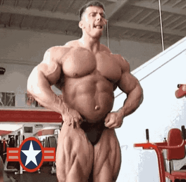 a very muscular man is posing for a picture in a gym in front of a star .