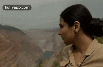 a woman is standing on top of a hill looking at the landscape .
