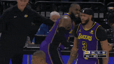 a man in a purple lakers jersey stands on the court