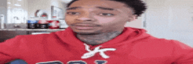 a man in a red hoodie is making a face .