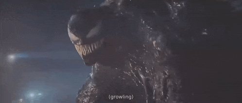 a close up of venom in a dark room with the words `` growing '' written below him .