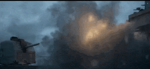 a battleship is firing a cannon at another ship in the ocean .