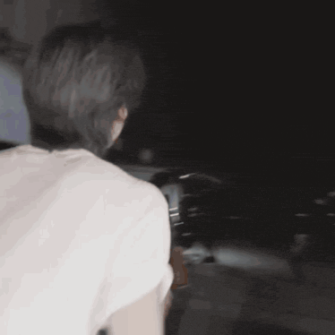 a man in a white shirt is running in the dark with a flashlight