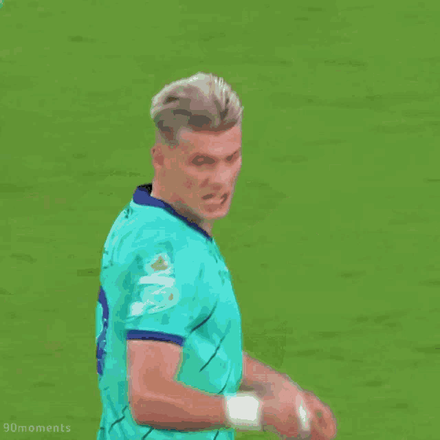 a soccer player wearing a green shirt with a blue mc logo on it