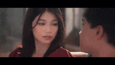 a woman in a red dress is looking at a man in a black shirt