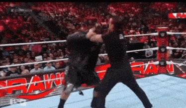 two men are fighting in a wrestling ring with a crowd in the background .