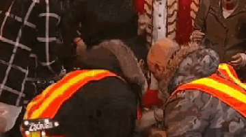 a man in a camouflage jacket is kissing a woman 's butt in a crowd .