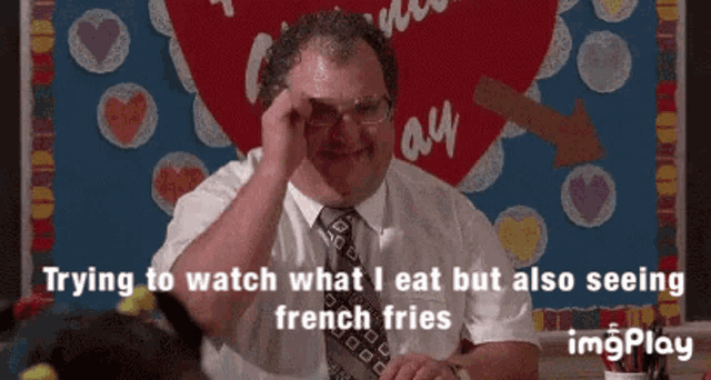 a man in a suit and tie is trying to watch what he eat but also seeing french fries ..